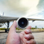 Selected,Focus,At,Hand,Of,Aircraft,Mechanic,And,Blurry,Aircraft